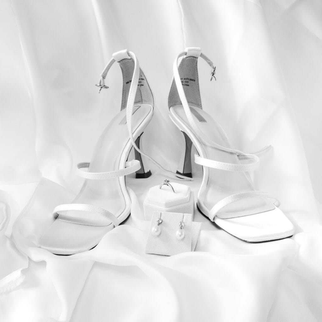 Shoes, earrings and engagement ring on white satin