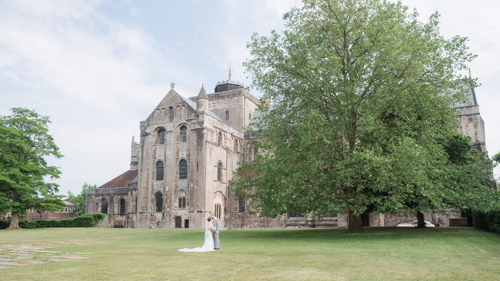 Bride and groom kiss in front of Romsey Abbey