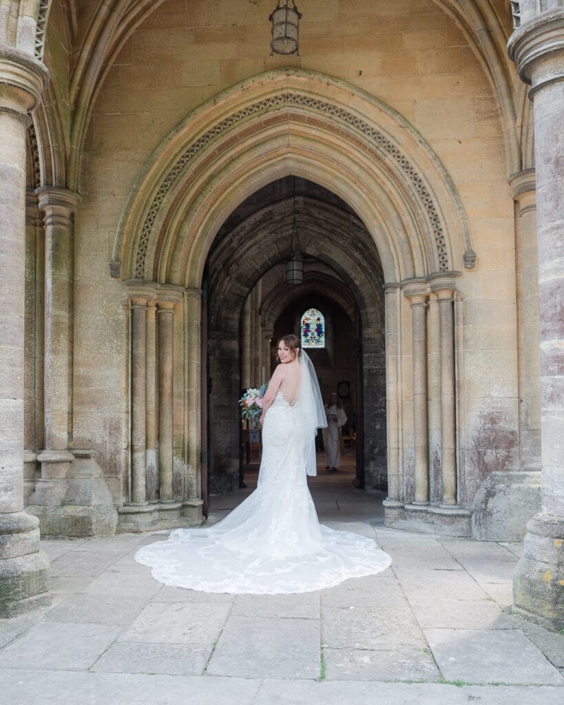Bride smiles over her shoulder in the north porch at Romsey Abbey