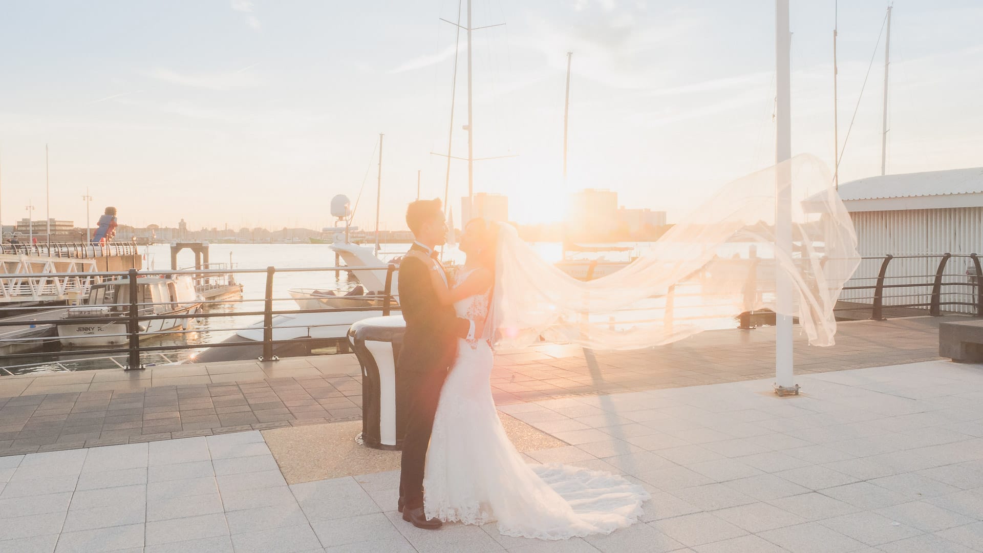 Brides veil flies behind her as she kisses her groom on the waterfront at Gunwharf Quays, Portsmouth.
