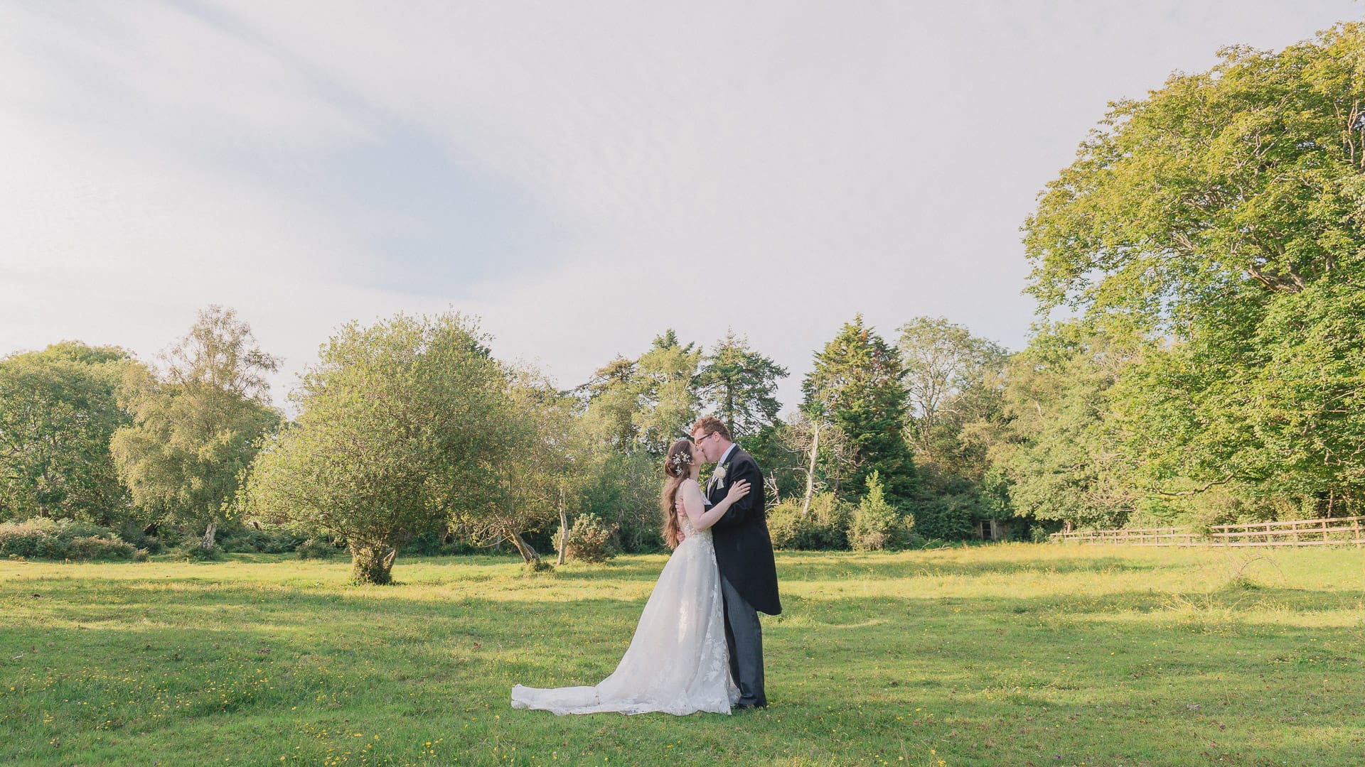 Bride and groom kiss in a New Forest meadow outside Carey's Manor
